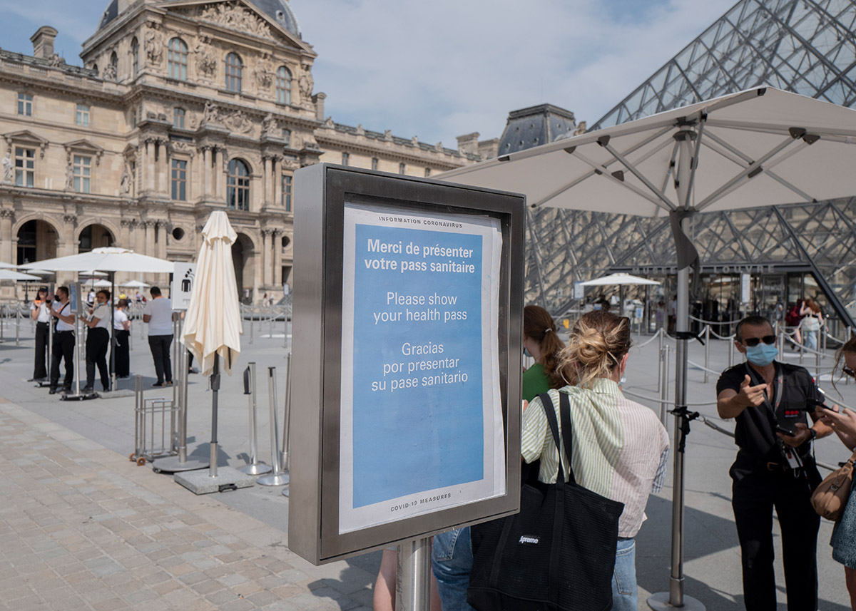 Besucherinnen und Besucher registrieren sich am 23. Juli 2021 für einen COVID-19-Test im Louvre-Museum in Paris.  Ein Schild weist auf den speziellen COVID-Ausweis hin, der für einen Besuch in öffentlichen Einrichtungen wie Museen oder Kinos in Frankreich nötig ist. Foto: Keystone-SDA / AP Photo/ Rafael Yaghobzadeh 