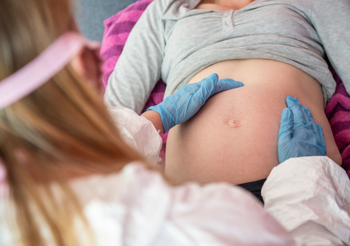 [Symbolbild] Eine Hebamme in Schutzausrüstung untersucht am 30. April 2020 in Nordrhein-Westfalen, Deutschland, eine schwangere Frau. Mangels Kenntnisse hat die Schweizer Behörde die Covid-Impfung Schwangere vorerst von der Impfung ausgeschlossen. Foto: Keystone-SDA / DPA / Caroline Seidel