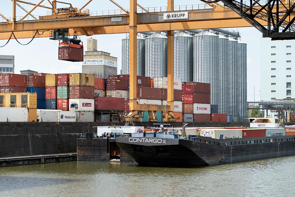 Container werden am Contargo Container-Terminal im Hafen Basel-Kleinhüningen im Juli 2020 auf ein Frachtschiff umgeschlagen. Die Schweiz importiert mehr Güter, welche im Ausland CO2 ausstossen, als sie exportiert. Foto: Keystone-SDA / Gaëtan Bally 