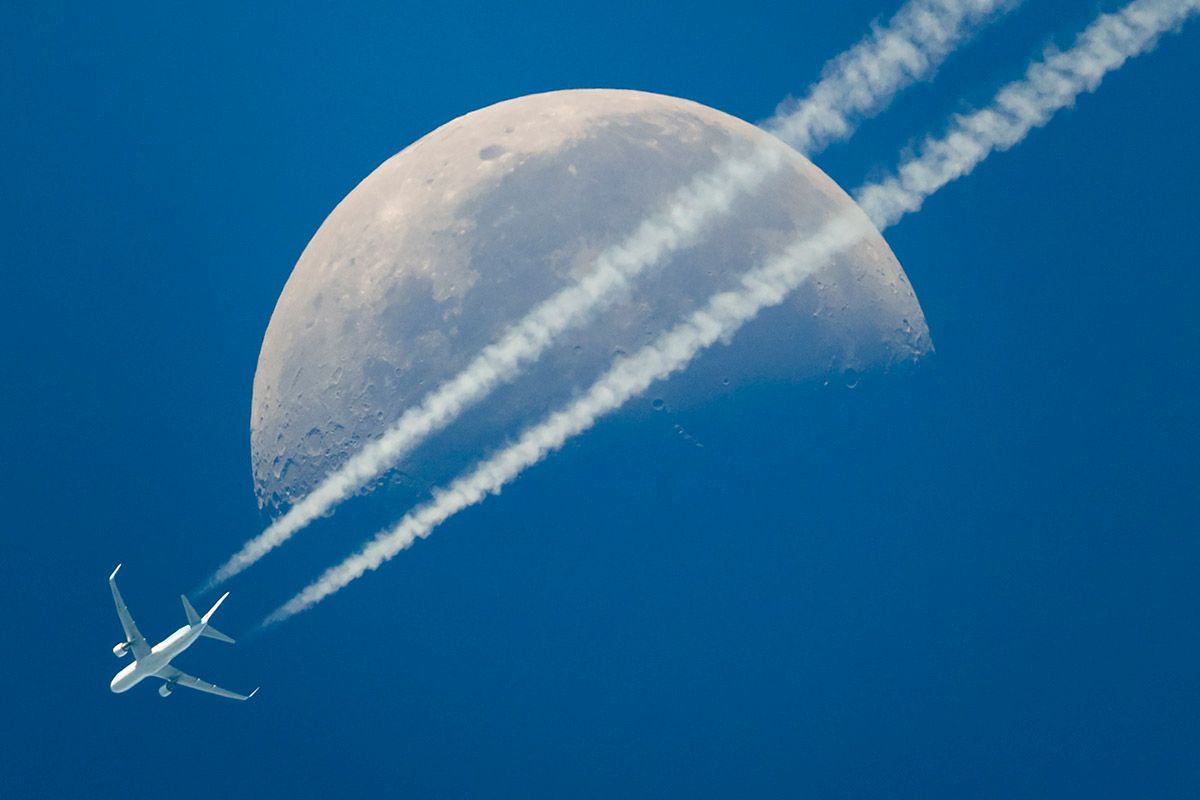 Flugzeuge versprühen nicht systematisch Chemikalien in die Atmosphäre: Kondensstreifen eines Verkehrsflugzeugs am 17. Juni 2017 vor grossem Mond über Genf. Foto: Keystone-SDA/Valentin Flauraud