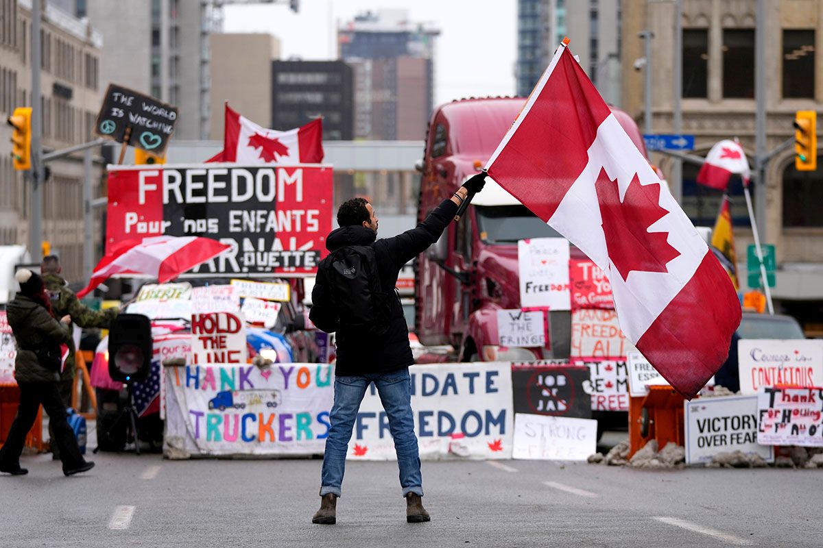 Ein Demonstrant schwenkt am 11. Februar 2022 eine kanadische Flagge vor geparkten Fahrzeugen in der Rideau Street in der kanadischen Hauptstadt Ottawa. Die Demonstrationen gegen COVID-19-Massnahmen haben sich zu einem breiteren Protest gegen die Regierung ausgeweitet. Ans Aufgeben wird nicht gedacht. Foto: KEYSTONE/ AP Photo/ Canadian Press/ Justin Tang / The Canadian Press