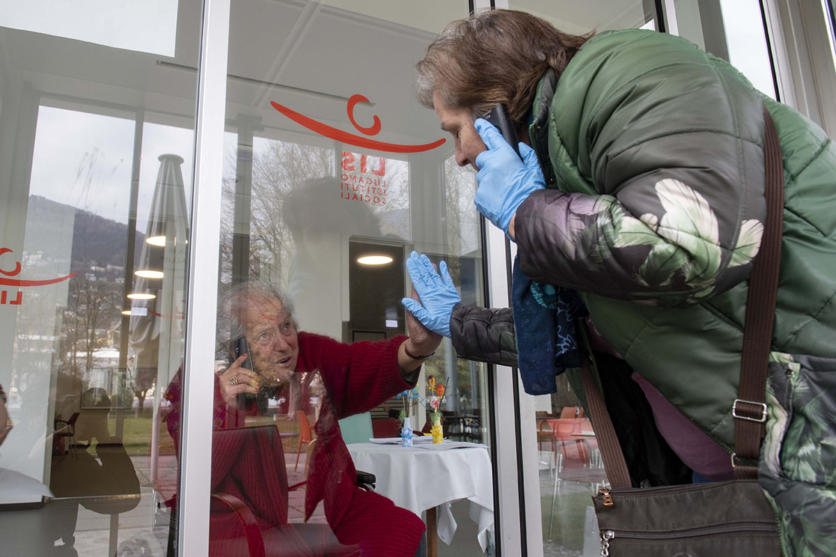 413152222 – Keystone-ATS/Ti-Press/Davide Agosta - Le 1er avril 2020,  Monica parle à travers une vitre à sa mère Giuseppina, 88 ans, qui vit dans la maison de retraite Serena à Lugano. En raison du virus corona, le contact direct est évité.