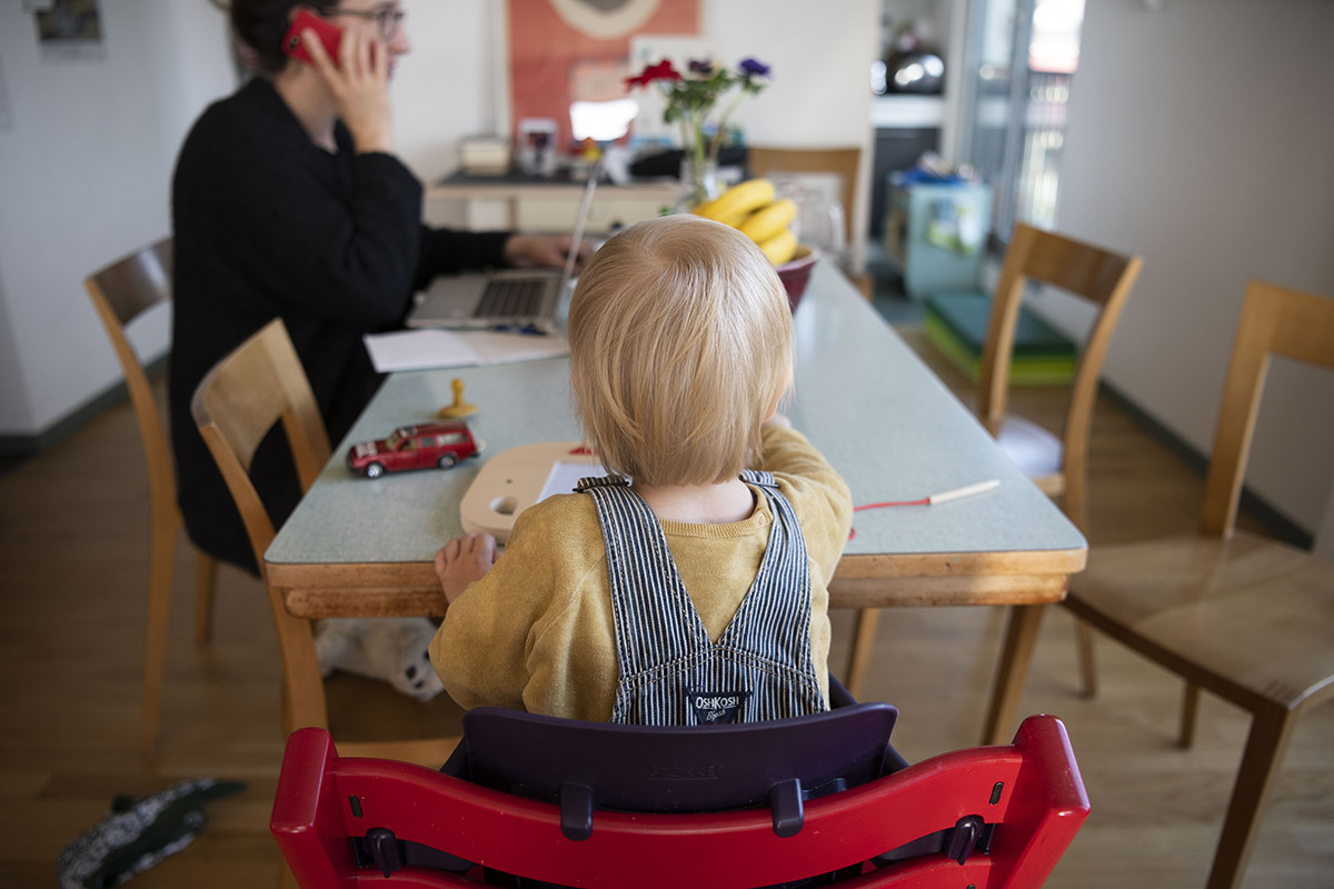 411605853  - Keystone-SDA/Christian Beutler - A mother working from her home office with her child. Because of the coronavirus pandemic, the Federal Council has massively restricted public life. People are encouraged to work from home if possible. Zurich,15 March 2020.