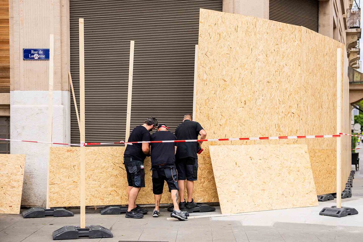 Des ouvriers installent des planches de bois devant les vitrines d'un etablissement pour le proteger d'eventuelles degradations de la part de manifestants durant la manifestation NoG7 liee au sommet du G7, a Evian-les-Bains en France, 