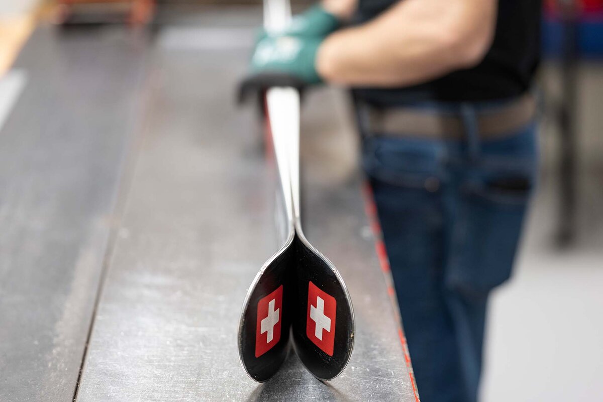 Ein Mitarbeiter richtet die Skipaare aus, damit sie perfekt schliessen. in der Skimanufaktur der Stoeckli Swiss Sports AG