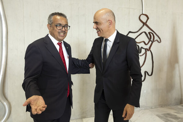 Tedros Adhanom Ghebreyesus, left, Director General of the World Health Organization (WHO), and Swiss Interior Minister Alain Berset, right, smile past the artwork titled "Fruechte tragen" after unveiling of the monumental artwork, in margin of the 75th World Health Assembly at the World Health Organization (WHO) in Geneva, Switzerland