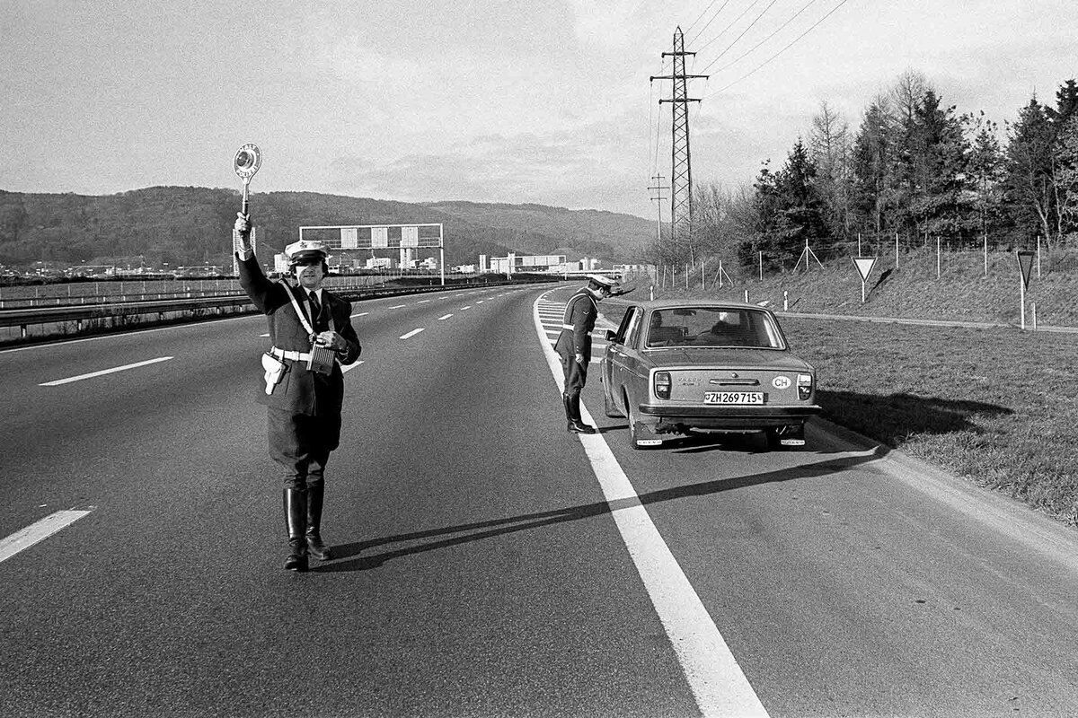 Eine Polizeipatrouille kontrolliert ein Auto an einem der Autofreien Sonntage im November/Dezember 1973 in der Schweiz. Wegen der unsicheren Versorgungslage auf dem Erdoelmarkt erlaesst der Bundesrat am 21. November 1973 ein Autofahrverbot fuer drei Sonntage und beschliesst eine voruebergehende Kontingentierung des Treibstoffs.