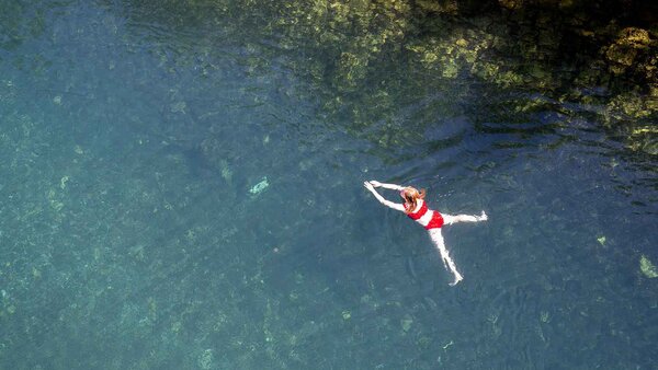 Eine Frau geniesst an einem Hitzetag die Sonne und schwimmt in der Limmat beim Flussbad Unterer Letten