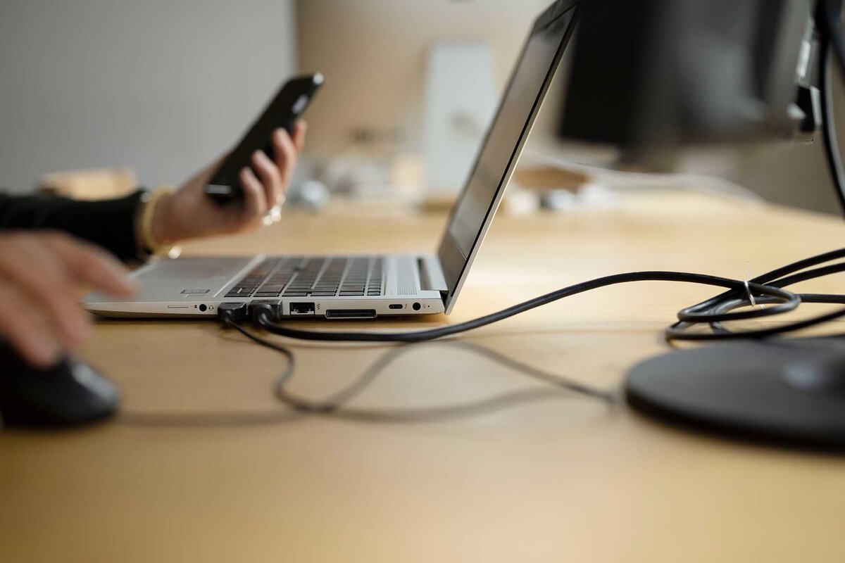 Eine Frau arbeitet an ihrem Arbeitsplatz im Homeoffice am Laptop und einem Smartphone,