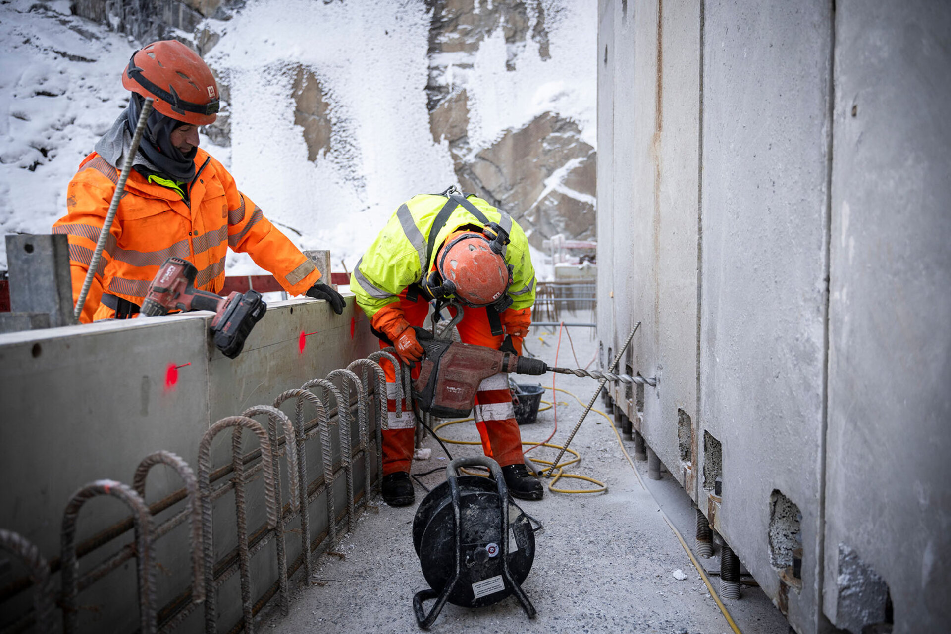 Deux ouvriers de chantier en tenue orange travaillent sur une structure en béton du barrage de Gigerwald d'Axpo.