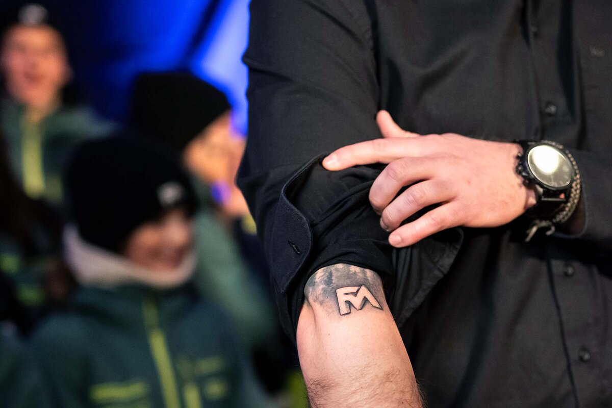 Ein Freund von Franjo von Allmen, dreifacher Olympiasieger an den Olympischen Spielen Milano Cortina, zeigt seine Franjo Taetowierung, die er sich aufgrund einer Wette hat stechen lassen