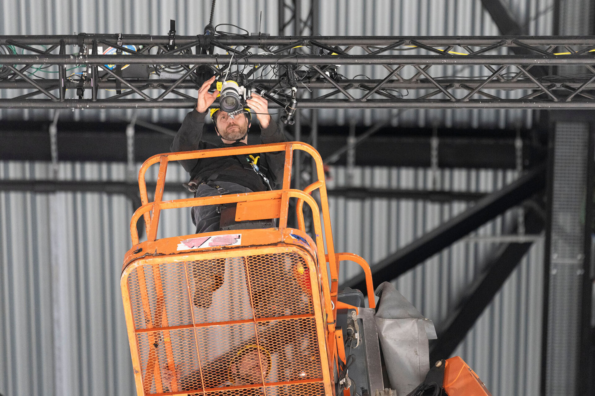 Michael Buholzer, Keystone-SDA photographer, is adjusting the remote-controlled camera 18 metres above the goal using a lifting platform, the camera will remain mounted on the ceiling of the Swiss Life Arena for the duration of the Ice Hockey World Championship