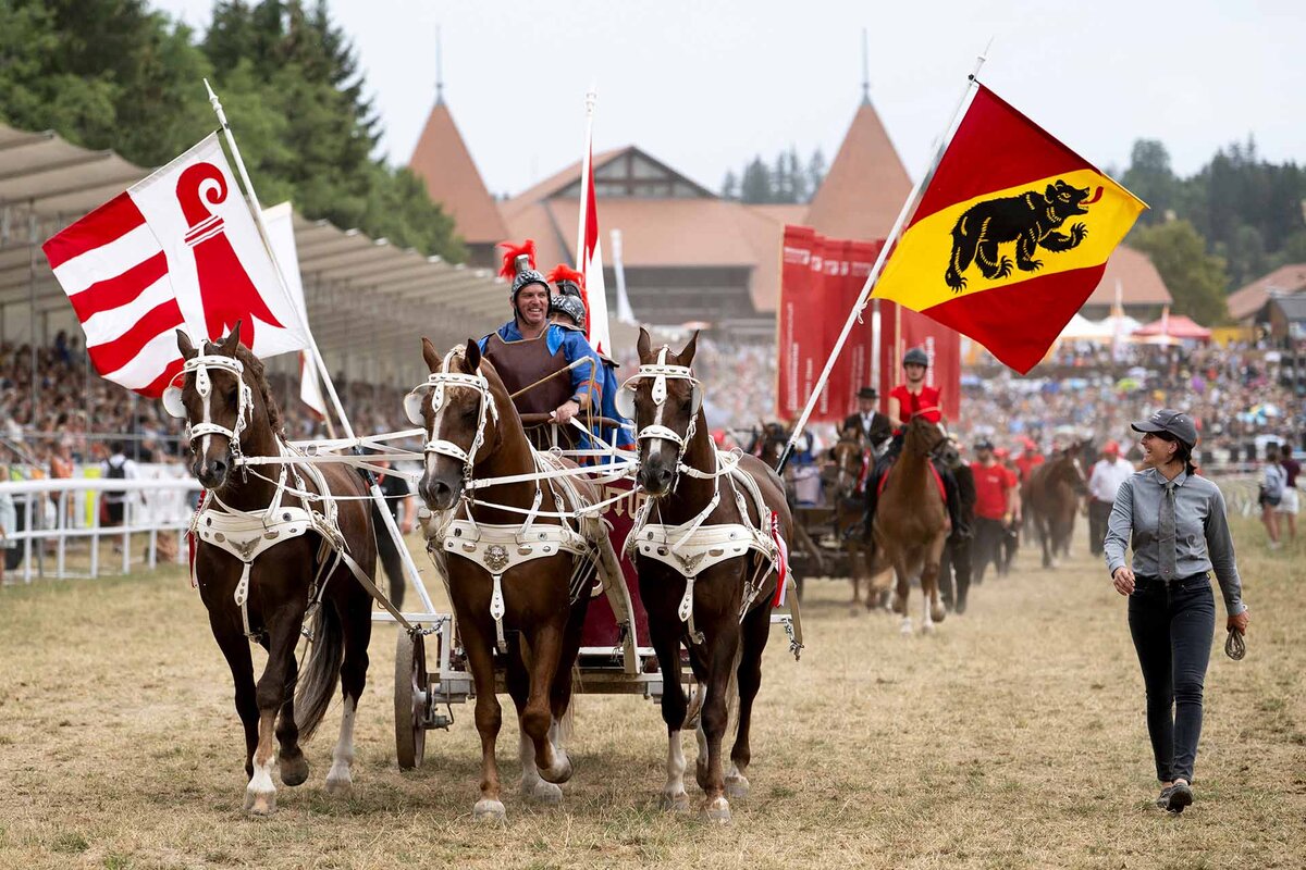 Des cavaliers defilent avec leurs chevaux avec le drapeau Jurassien et le drapeau bernois lors du grand cortege folklorique, lors du grand cortege folklorique du 121e Marche-Concours national de chevaux, dimanche 9 aout 2026, a Saignelegier.