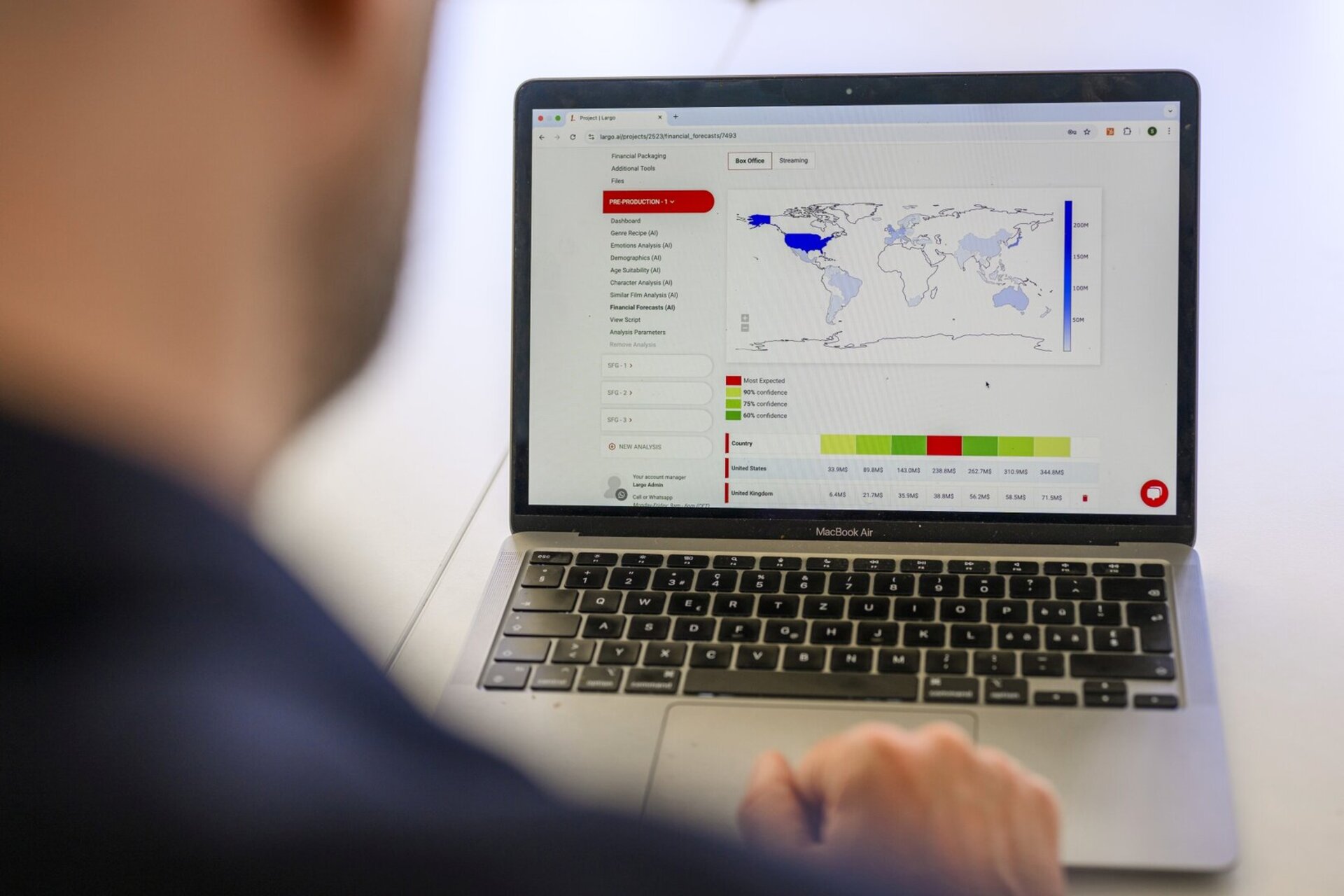 Une personne travaille sur un ordinateur portable, l'ecran affiche des visualisations de donnees avec une carte du monde et des graphiques.