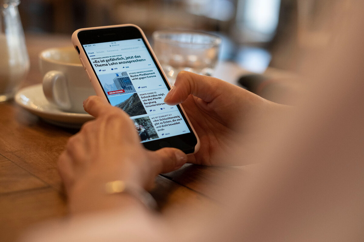 Une personne consulte en ligne le quotidien "20 Minuten" sur son smartphone dans un cafe.