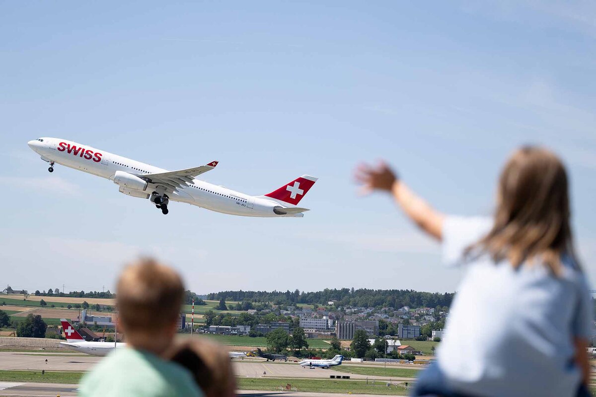 Ein Maedchen winkt auf der Zuschauerterrasse dem Airbus A330 der Swiss auf dem Flug nach Dehli.