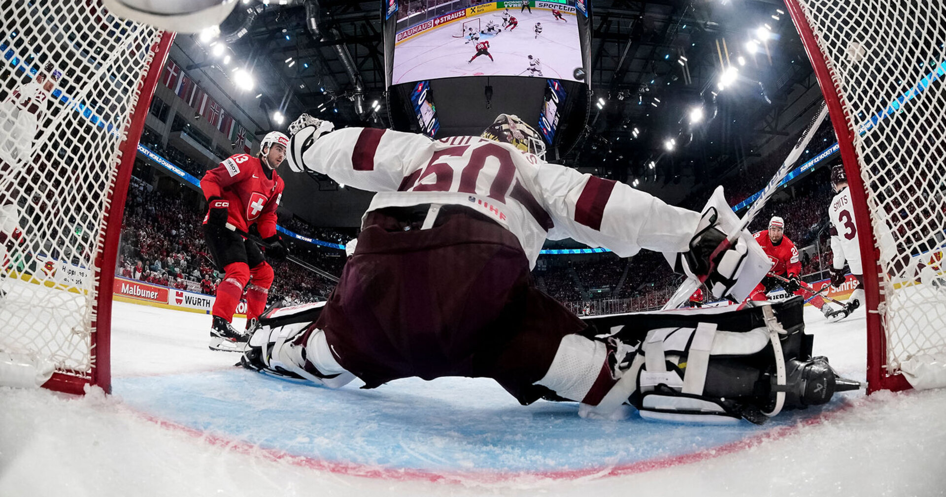 Switzerland's Timo Meier, right, misses a shot against Latvia's goaltender Kristers Gudlevskis, middle, during the 2026 IIHF Men's Ice Hockey World Championship preliminary round group A game between Switzerland and Latvia