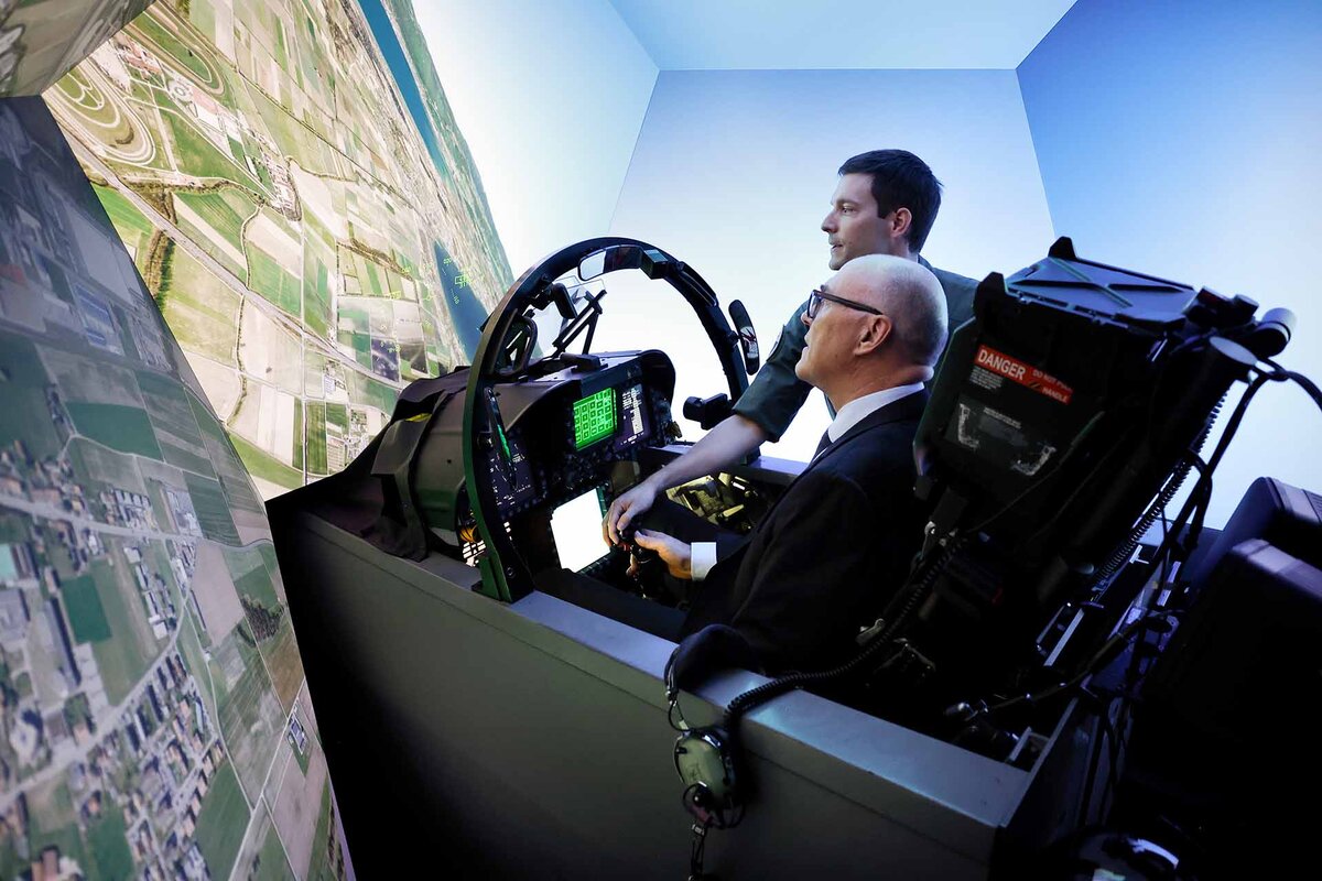 Bundesrat Martin Pfister (assistiert von Pilot Lucien Lassence) sitzt im Cockpit eines Flugsimulators, waehrend einem Rundgang auf dem Militaerflugplatz Payerne
