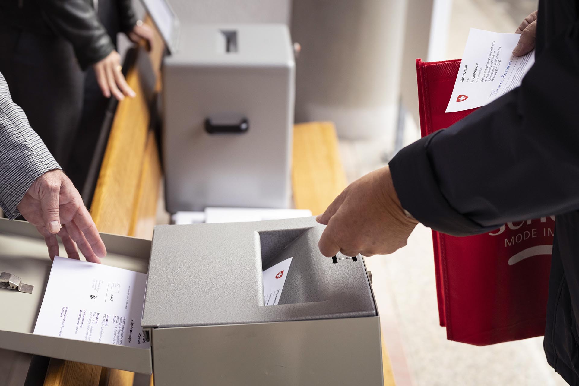 Des personnes glissent leur bulletin de vote dans l'urne pour les elections federales.