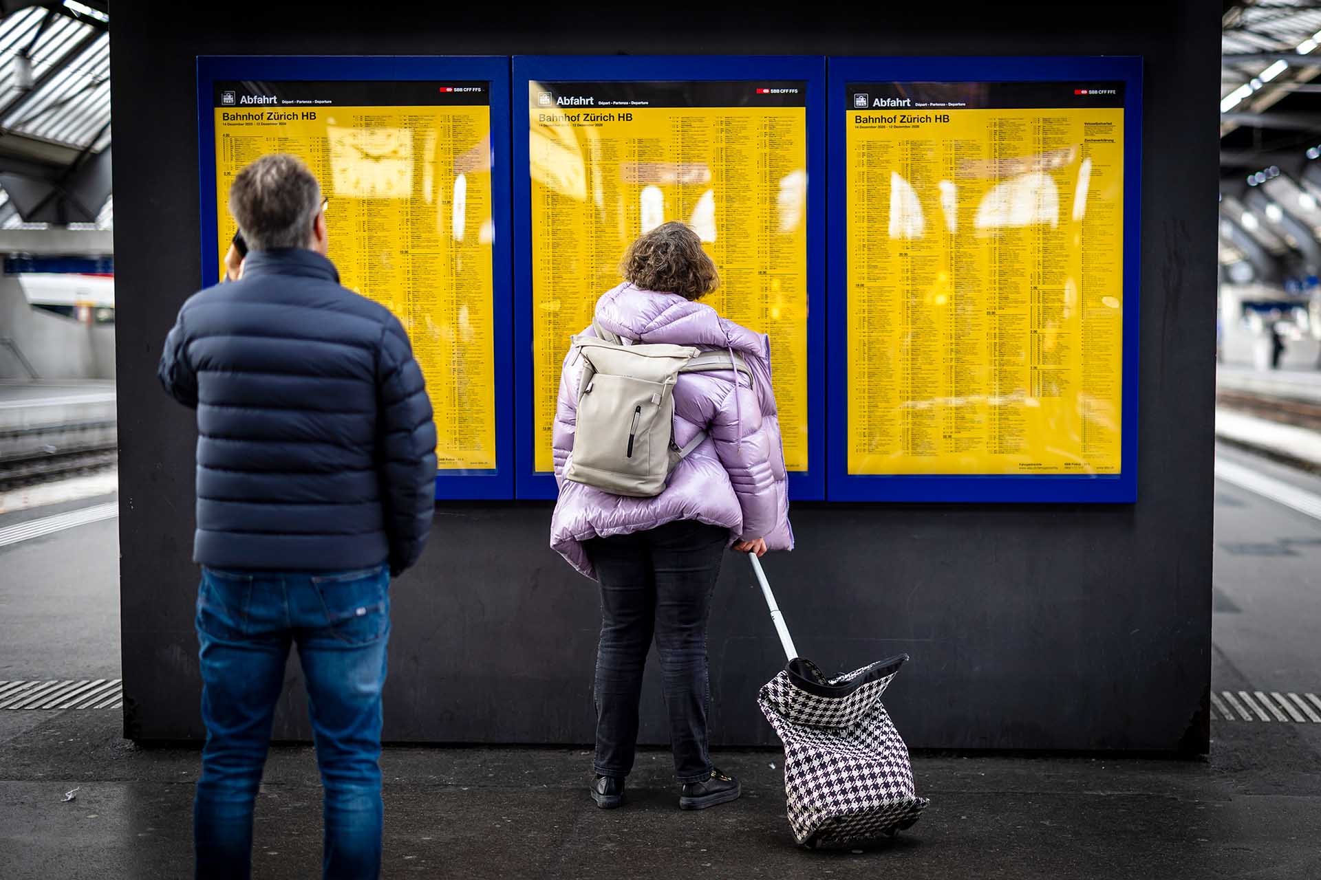 Deux personnes consultent les horaires de depart a la gare centrale de Zurich.