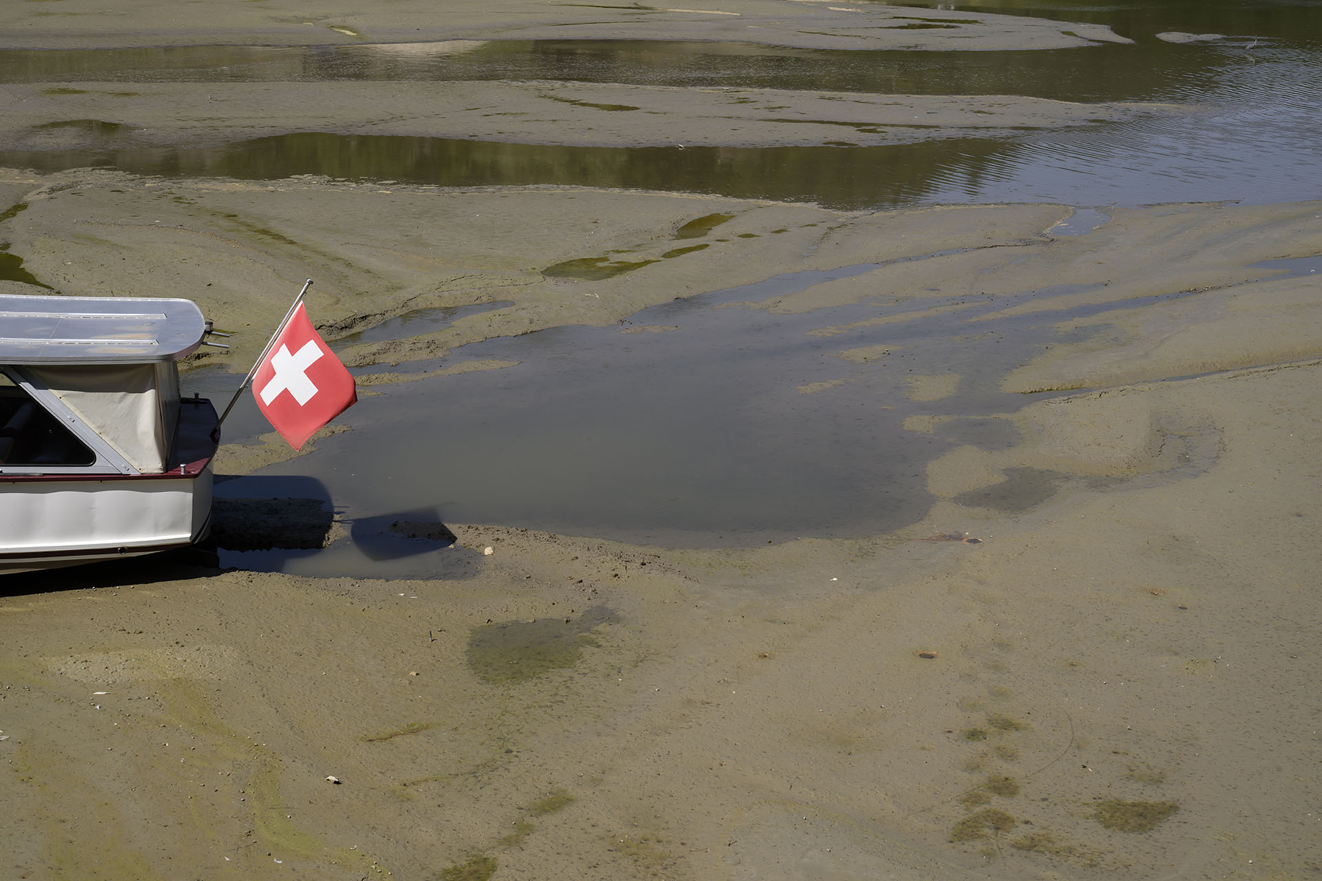 A Navigation Boat on the Lake of Brenets (French: Navigation sur le lac des Brenets) is trapped in the mud on the dried out shore of the Brenet Lake (French: Lac des Brenets) part of the Doubs river, a natural border beetwen eastern France and western Switzerland