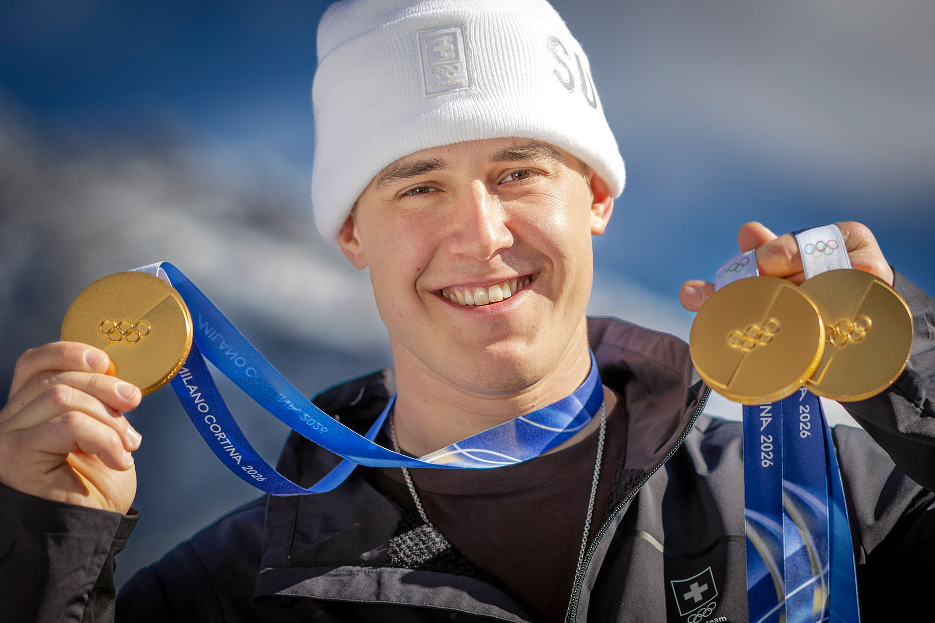 old medalist Franjo von Allmen of Switzerland poses for photographers with his three gold medals during a photocall outside the Swiss team hotel at the 2026 Olympic Winter Games at the Stelvio Ski centre in Bormio