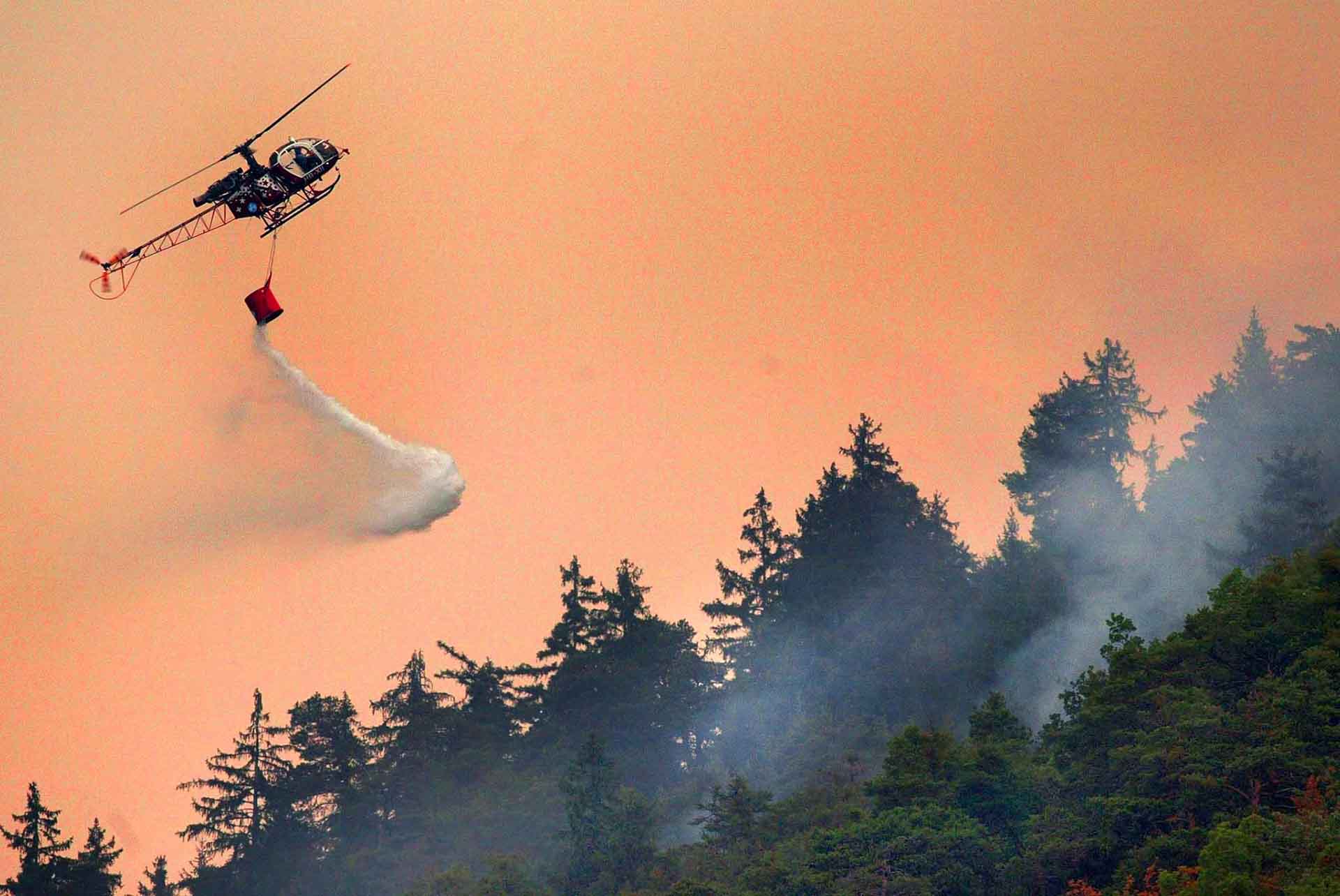 A helicopter fights against a wildfire, Thursday, August 14, 2003 at the border of the Swiss village of Leuk in southern Switzerland.